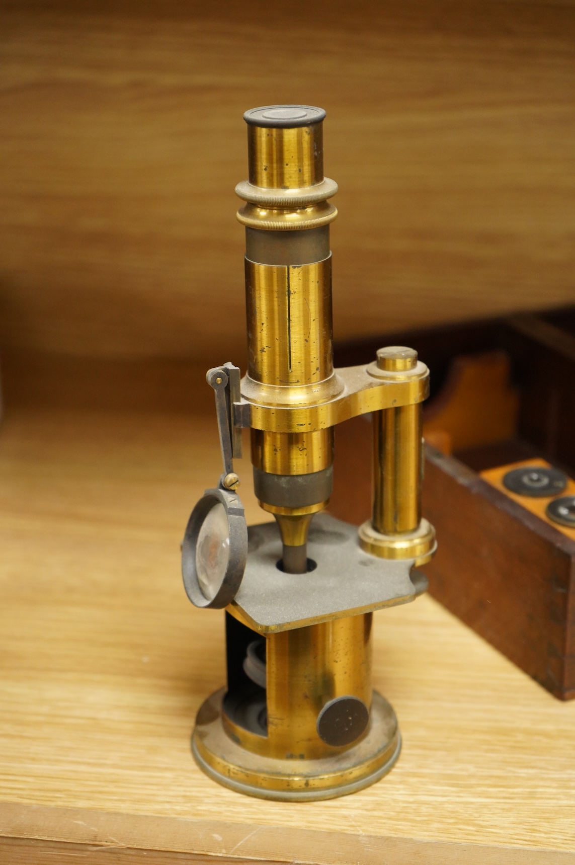A mid 19th century French brass compound monocular microscope, by Nachet, Optician, Rue Serpente 16, Paris, with two eyepieces, three objectives and several slides, mahogany cased, instrument height 23cm